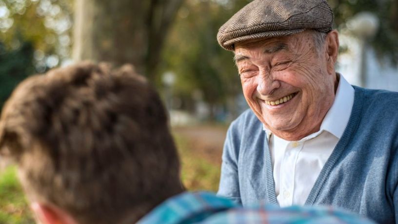 Older man laughing with a friend.