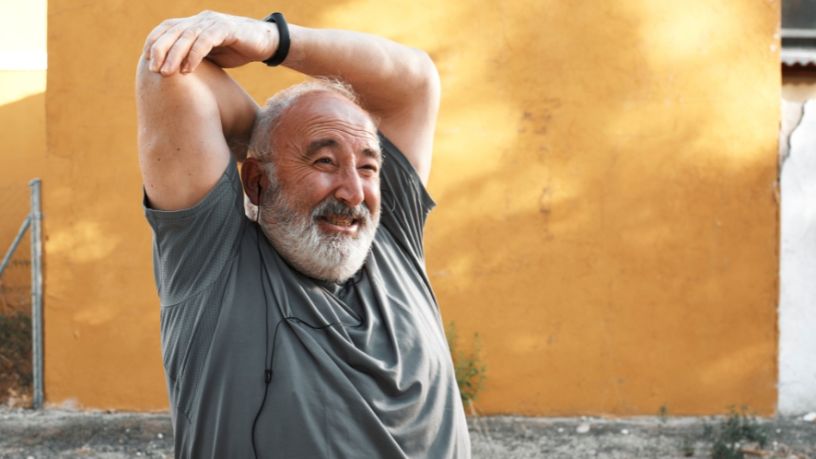 Man with a beard doing a tricep stretch.