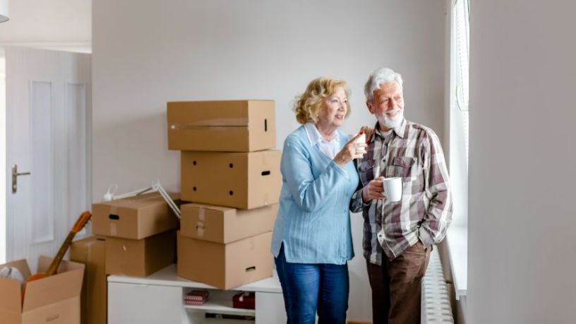 Mature man and woman have tea while packing moving boxes.