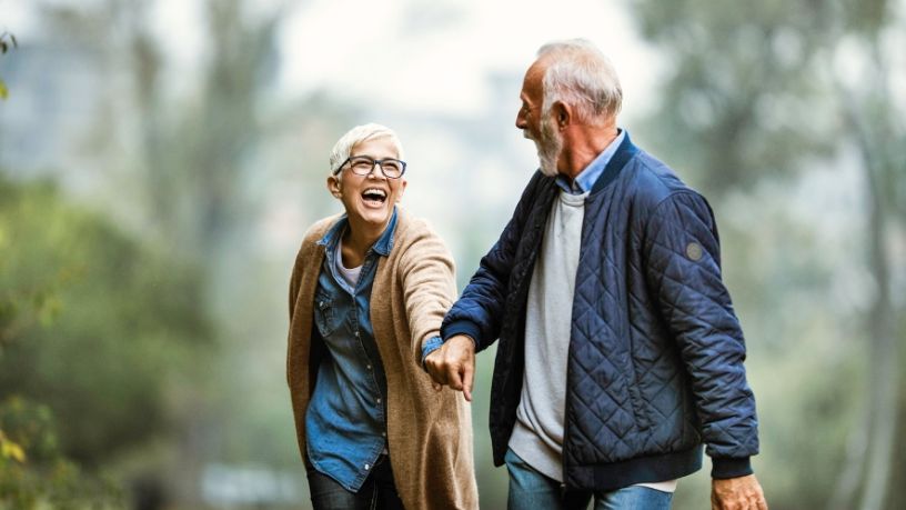 Mature aged man and woman laugh while on a walk