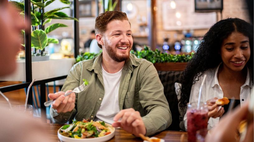 A man eating a salad with friends