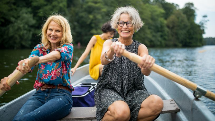 A group of women row a boat through a lake.