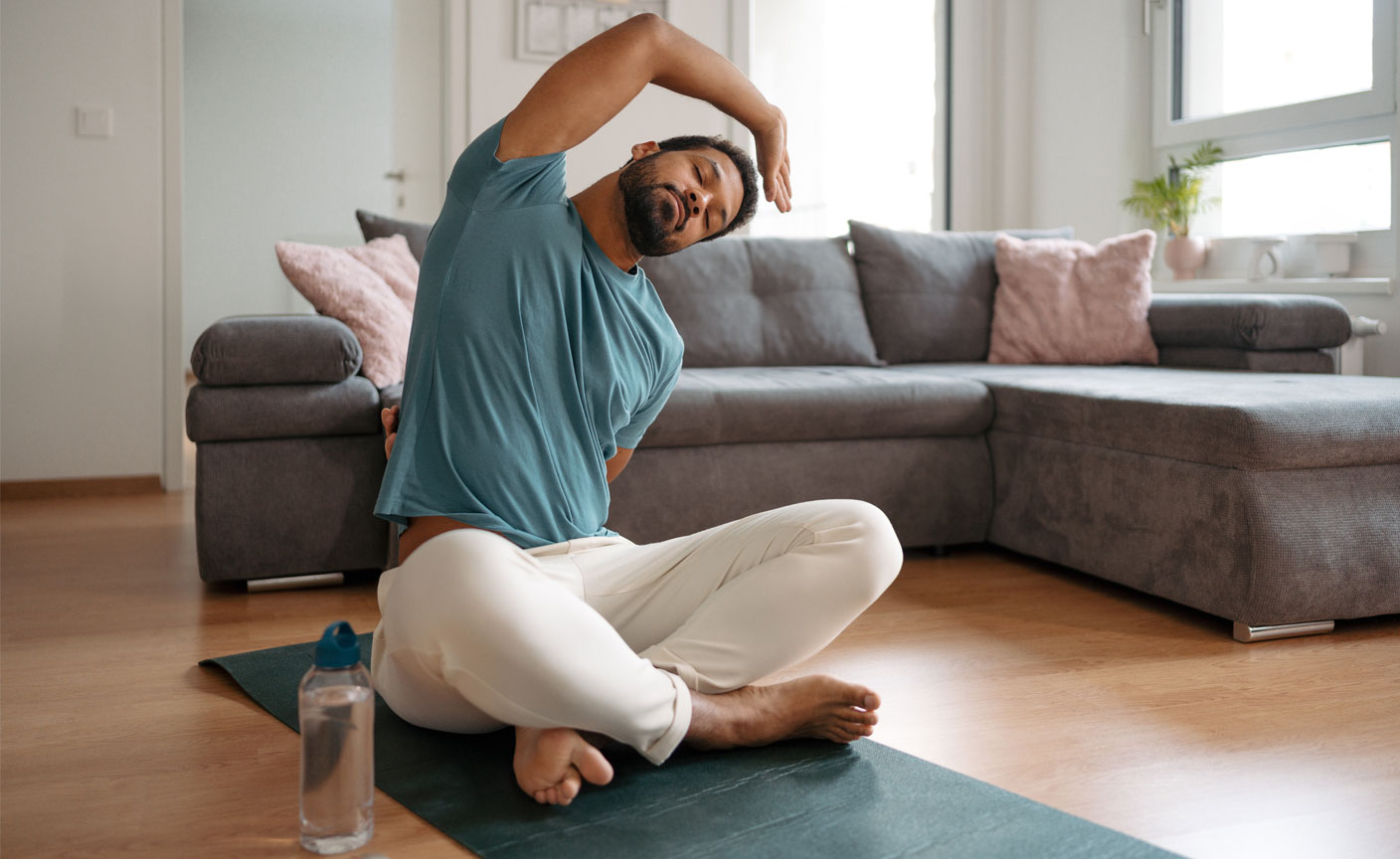 Man doing stretching exercises on exercise mat in living room