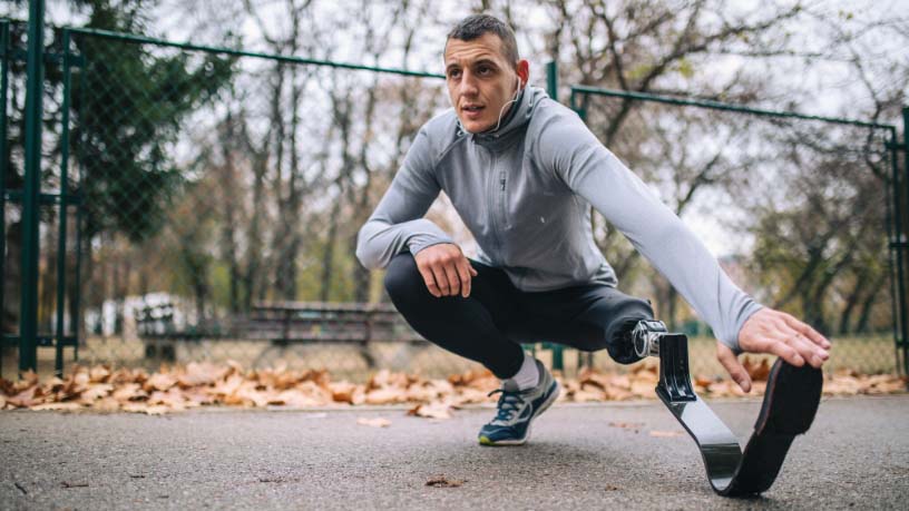 A man with running blades stretches his legs.