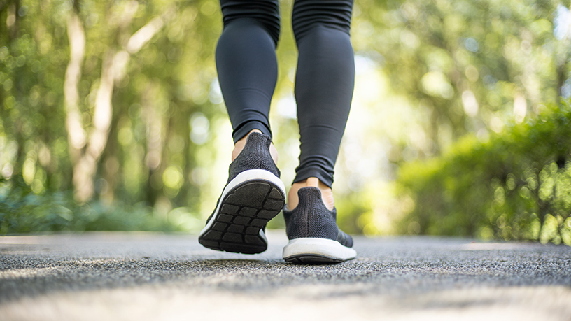 A woman walking in nature with the focus on her shoes.