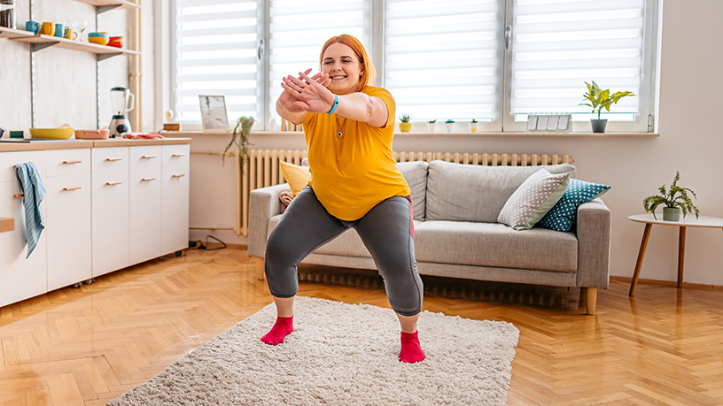 A woman in a yellow top doing squats.