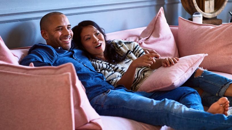 Two people cuddle excitedly on the couch.
