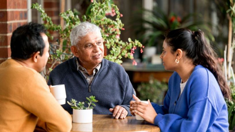 Three people deep in conversation over a warm beverage.