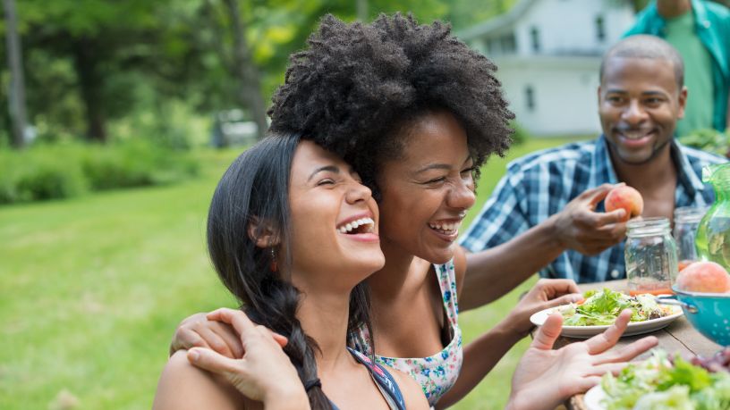 Friends laughing and enjoying time together outside over good food.