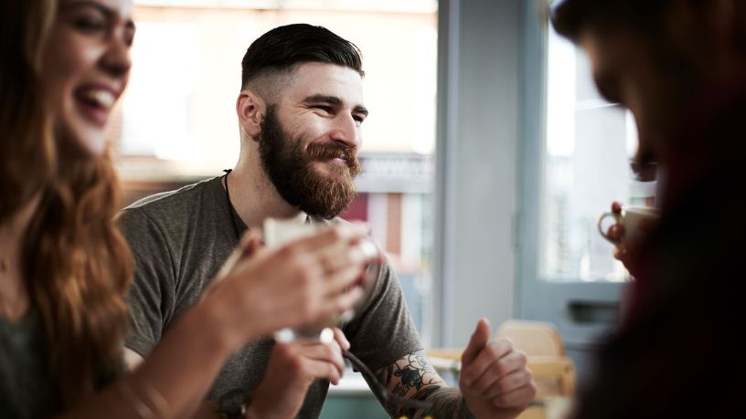 Man and woman sitting with friends with glasses in hands