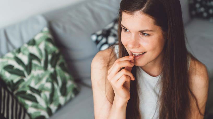 A woman smiles while taking a pill.
