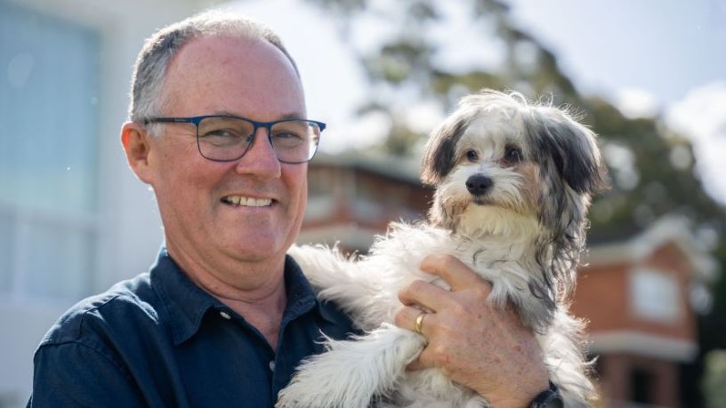 Man smiling and holding a puppy.