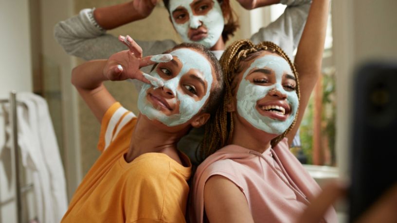 Three friends with face masks strike a pose and take a selfie.