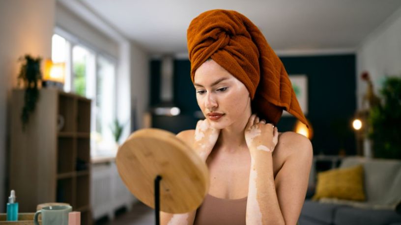 A woman freshly out of the shower looks into a mirror.