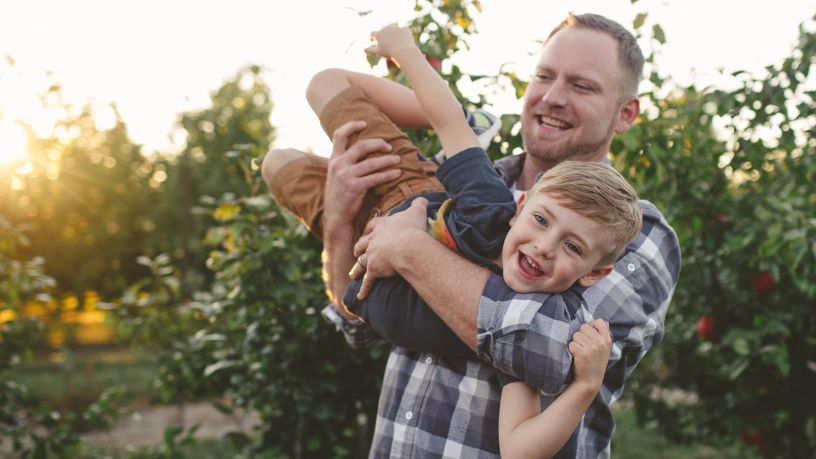 A little boy is whisked through the air by his dad.