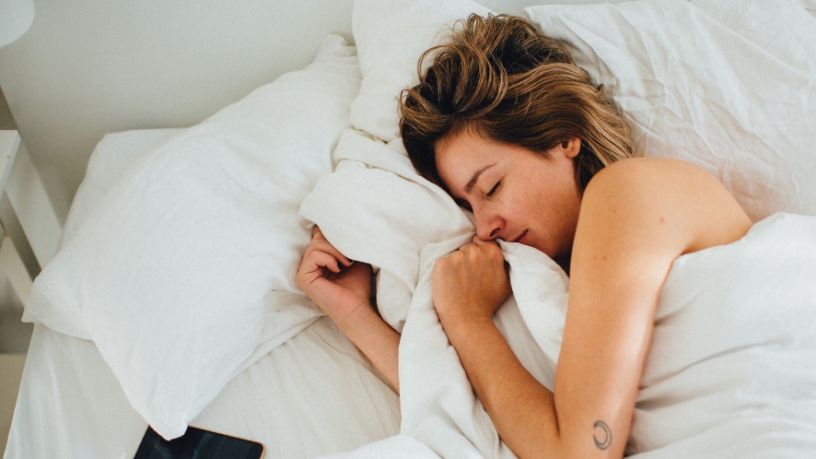 Woman asleep in bed with white covers.