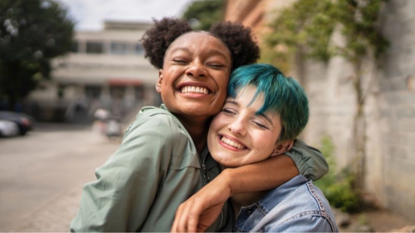 Two women hug and grin at the camera.