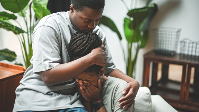 A man hugs his friend to his chest.