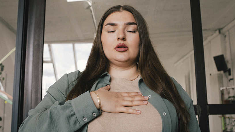 A woman focusing on breathwork or having an anxiety attack.