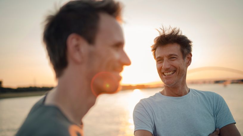 Two men standing together in the afternoon light. 