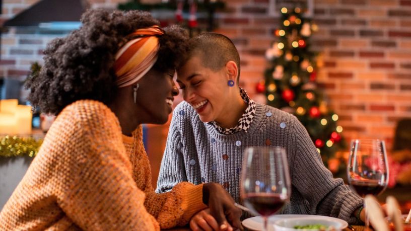 A festively dressed couple share a happy and intimate moment at a restaurant.