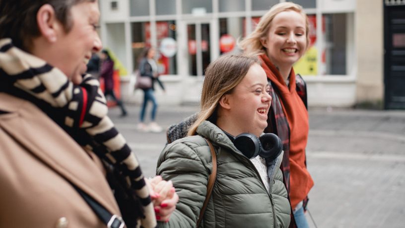 Three friends walk down the street and laugh.
