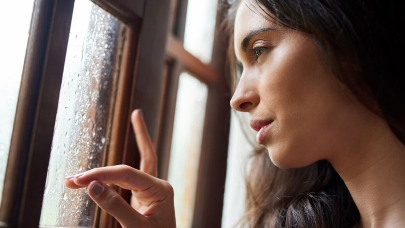 Woman looking through a rain-covered window