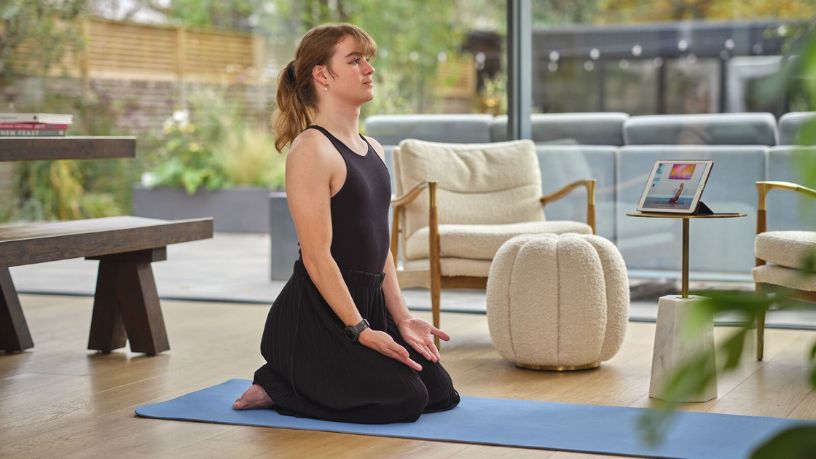 Woman sitting on the ground with spine straight with hands on thighs