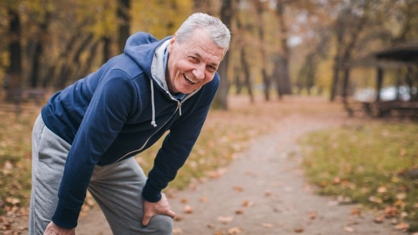 Jogger in park rests his hands on his knees.