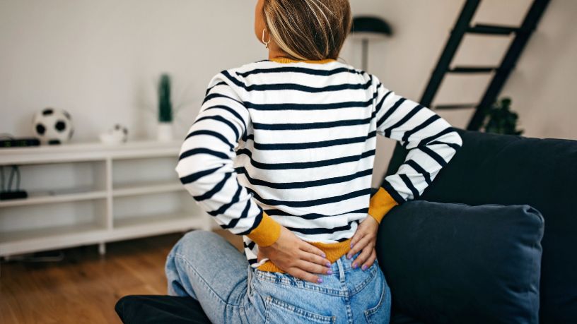 A man sits with his dog on his lap while looking at his phone. 