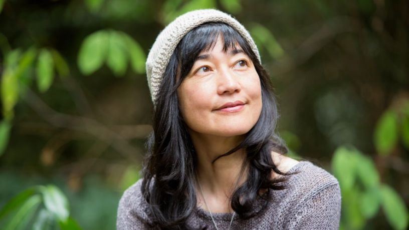 A woman looks off to the side of the camera while standing outside. 