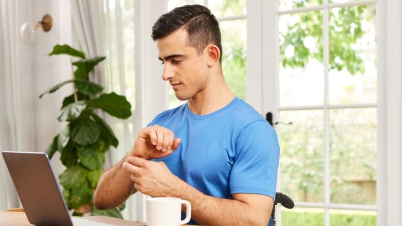 A man sits in front of his laptop and massages his sore wrist.
