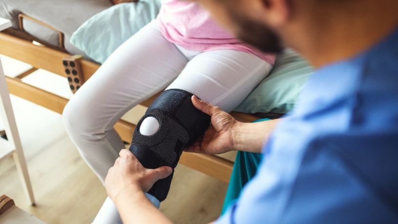 Physiotherapist checks a patient’s injured knee.