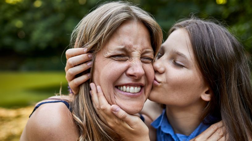 A girl kisses her mum on the cheek.