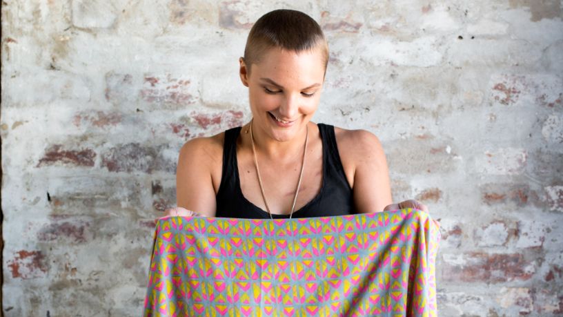 Emily holds a patterned scarf in front of her body.