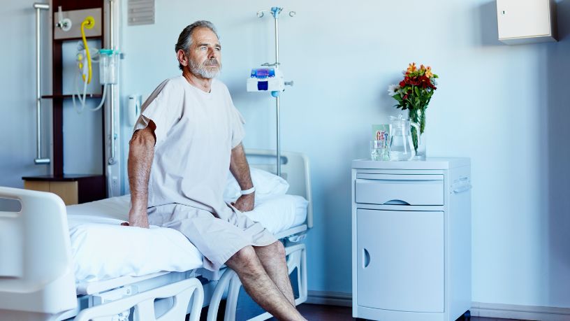 Man sitting on a hospital bed gazing into the distance.