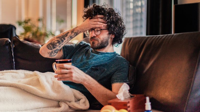 Man on the couch looking very unwell with the flu.