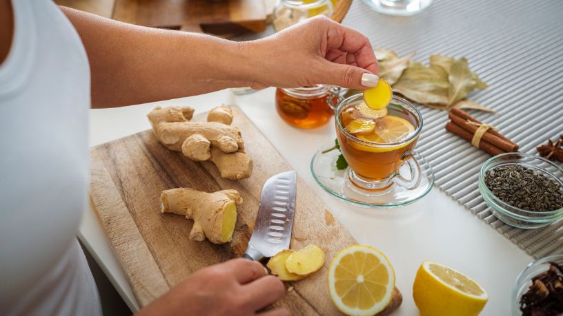 A woman in the kitchen making a lemon and ginger tea.