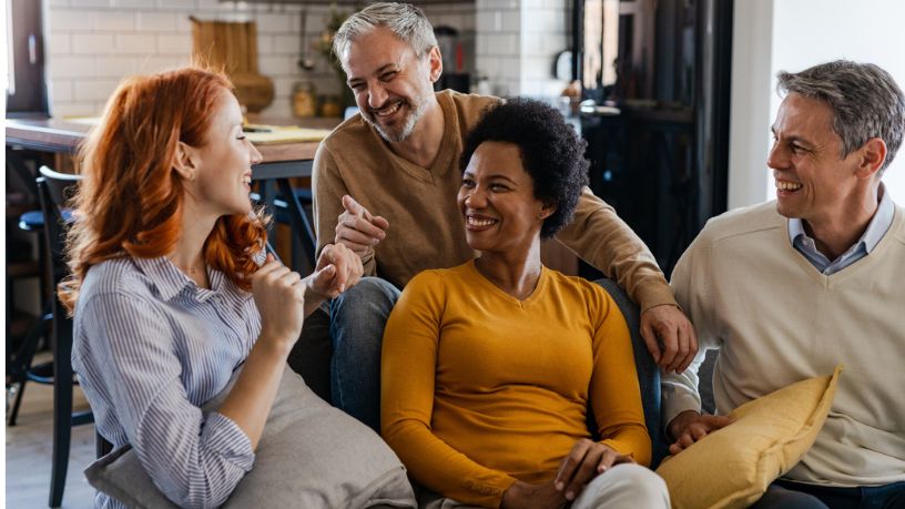 Group of mid adult friends laughing and catching up at home