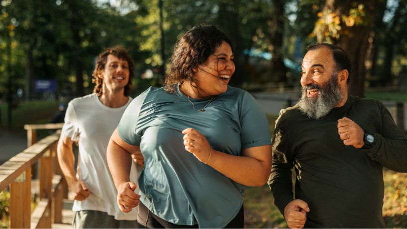 Older man jogging and laughing with his daughter in a park
