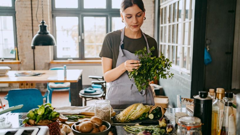 A woman preparing a healthy meal with lots of vegetables.