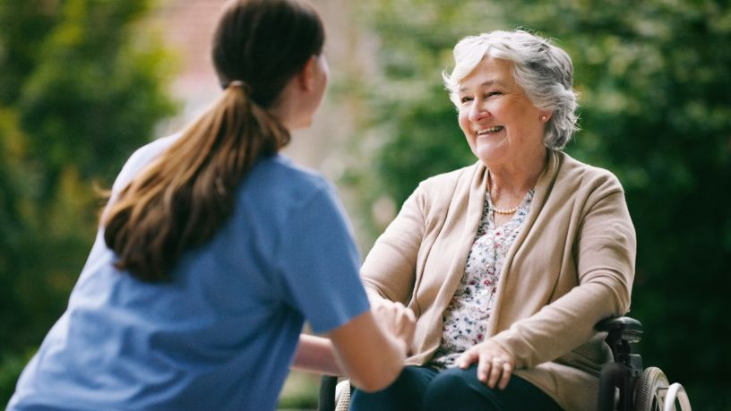 A care worker speaks with a smiling woman.