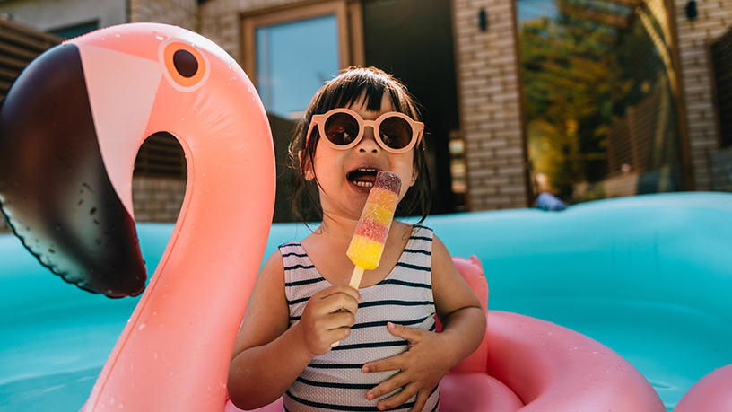 Child wearing sunglasses sitting on a swimming floater under the sun