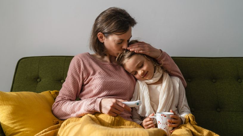 A woman holds her sick child and kisses her head.
