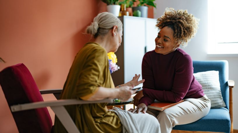A patient speaks with a woman in her office.
