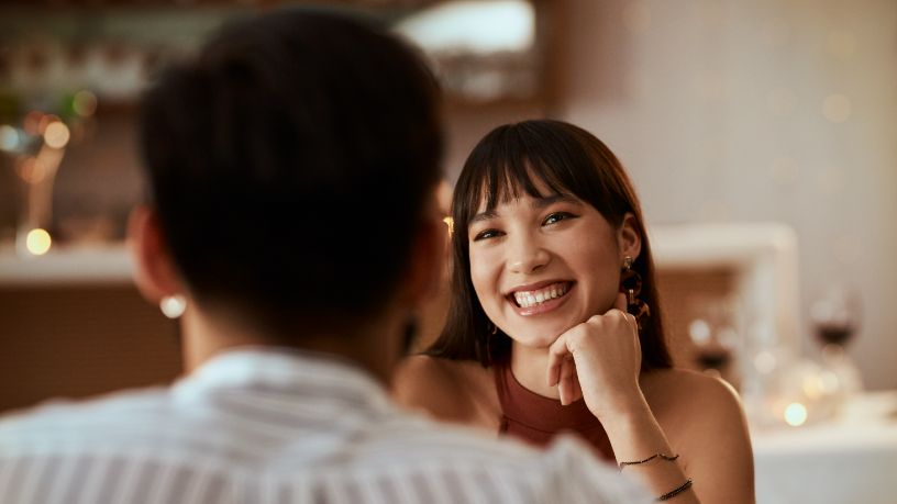 A woman at a restaurant smiles at her partner.