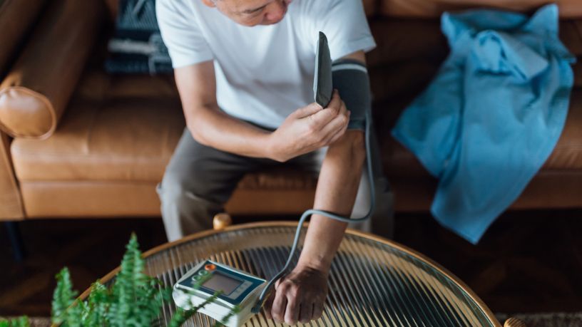 Senior man checking his blood pressure at home on his arm with a blood pressure monitor