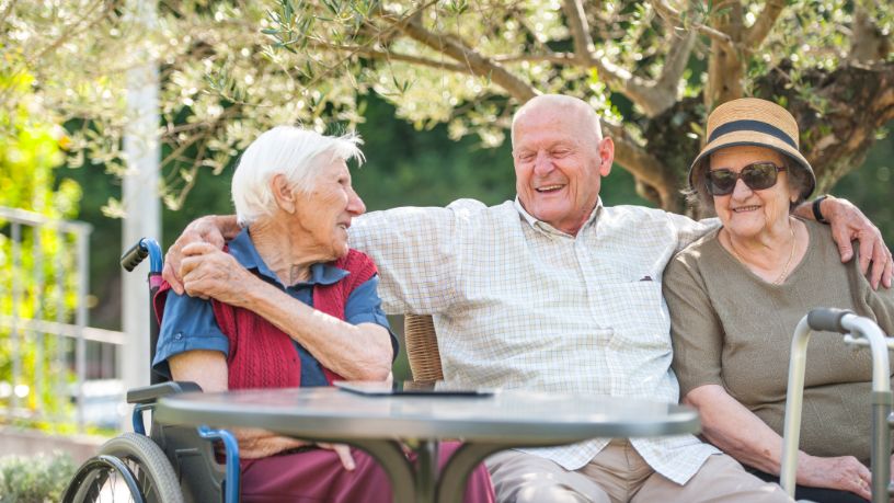 A man sits with his arms around two women at a park.