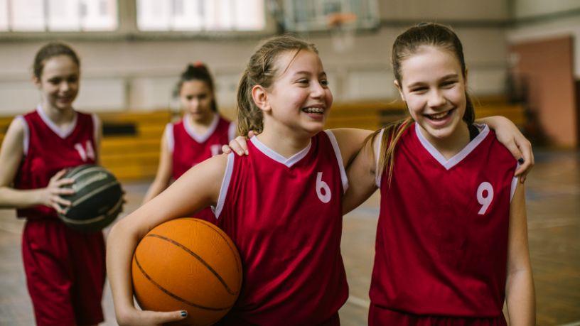 Two girls with their arms around each other's shoulders at basketball.