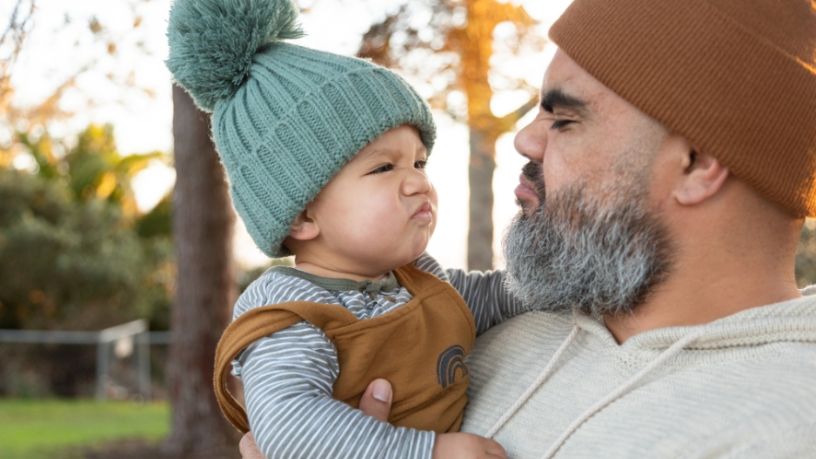 Cute baby and dad pull faces at each other.